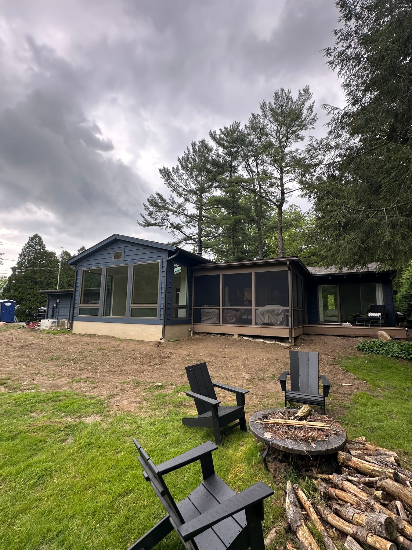 A modern renovated home exterior in dark siding with a screened porch, under a moody sky