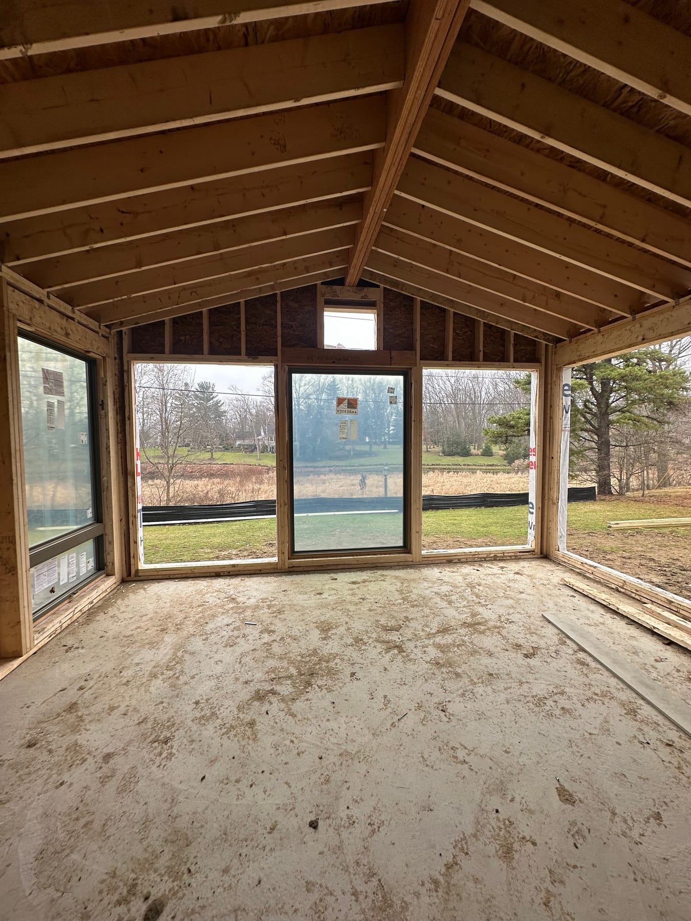 A porch addition mid-frame with exposed rafters looking onto an open field