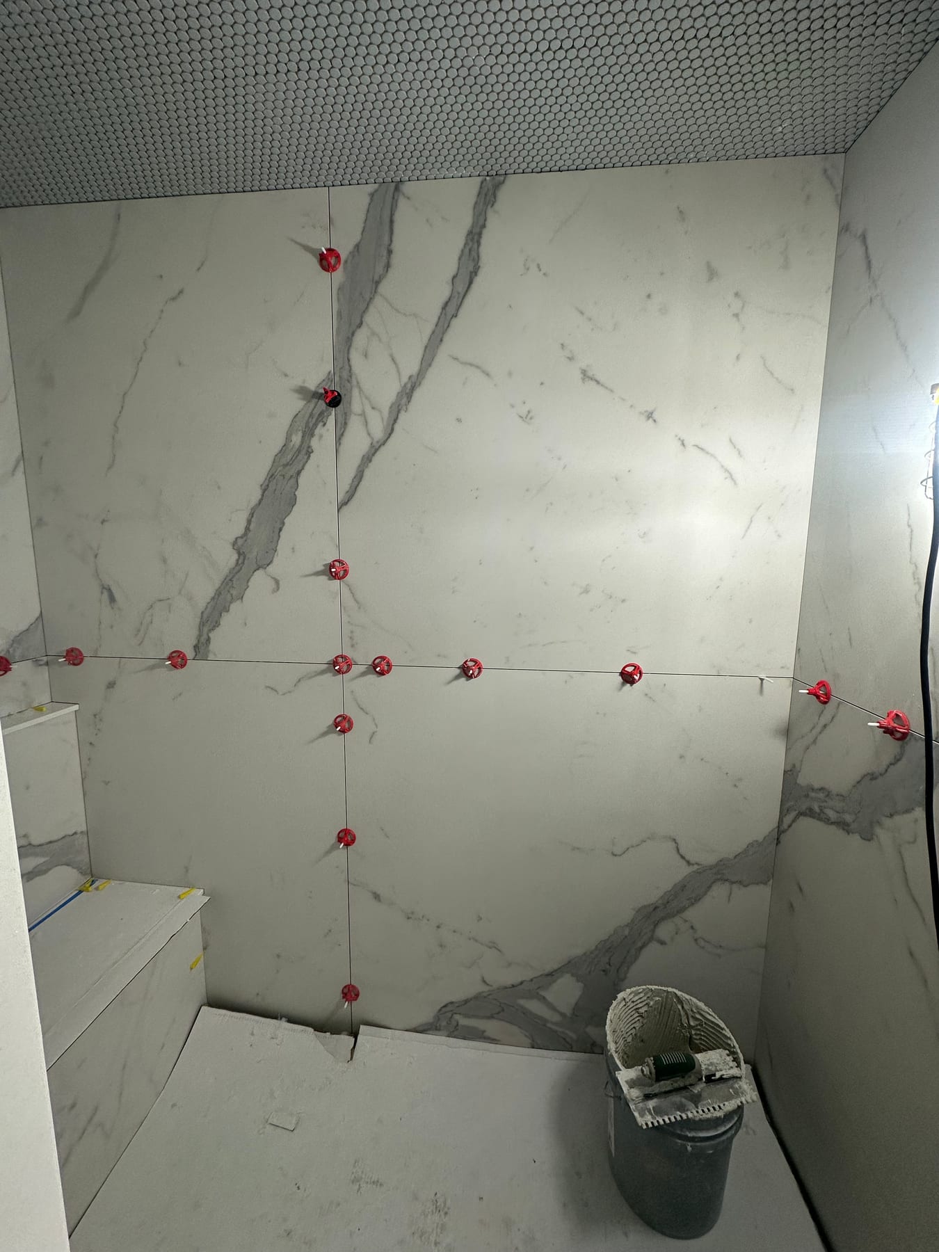 Large marble-look slabs laid out and marked for cutting during a bath install