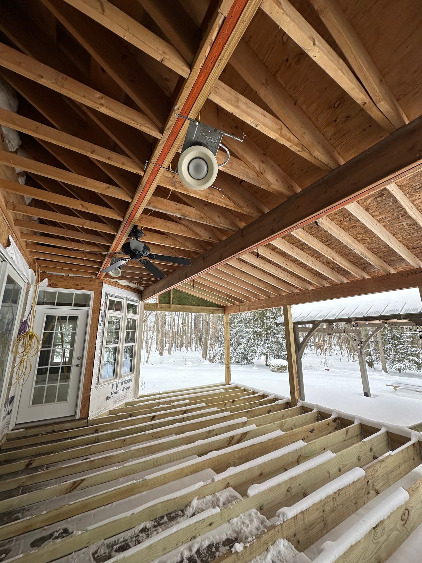 Exposed porch framing under a fresh snowfall on a JR Signature Homes project
